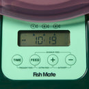 Eine Nahaufnahme des grünen Bedienfelds des Fish Mate Futterautomaten, die ein lcd-Display zeigt, das "10:19 am" anzeigt, mit drei Fischsymbolen darüber und vier Steuertasten darunter, die mit "time", "feed", "+" (advance feed) und "-" (auto off) beschriftet sind, sowie zusätzlichen Beschriftungen für "frequent feed" und "extra feed" unter den Tasten.