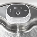 Draufsicht in Nahaufnahme auf eine weiße Steuereinheit eines Haustier‑Trinkbrunnens, die mittig in einem Edelstahlbecken montiert ist, mit einem schwarzen Touch‑Panel samt Batterie‑, Wireless‑, Timer‑ und Wassertropfen‑Symbolen rund um eine zentrale Ein/Aus‑Taste, sowie einem Wasserstrahl, der unterhalb der Einheit in das Becken fließt.